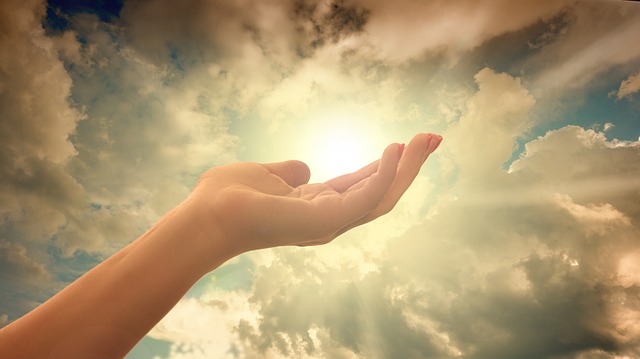A hand in front of a light, representing spirituality